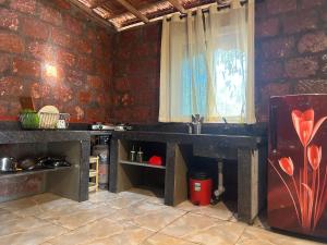 a kitchen with a brick wall and a window at Palm Breeze Suites in Palolem