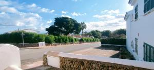una calle vacía con una pared de piedra al lado de un edificio en Casa Addaia Playa Arenal d'en Castell Beach, en Es Mercadal