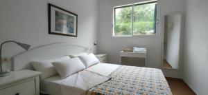 Un dormitorio blanco con una cama y una ventana. en Casa Addaia Playa Arenal d'en Castell Beach, en Es Mercadal