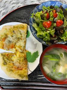 un plato de comida con una pizza y una ensalada en ペット可 Akiu-Canada 鴻ノ巣温泉 en Sendai