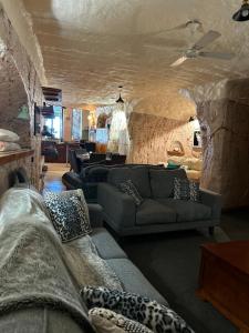 a living room with couches and a stone wall at Dinky Di's Dugout in Coober Pedy