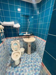 W wyłożonej niebieskimi kafelkami łazience znajduje się toaleta i umywalka. w obiekcie 日日 Meworld w mieście Beigang