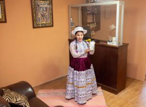 kobieta stojąca w pokoju trzymająca drinka w obiekcie Colibrí Inn w mieście Chivay