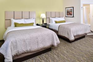 two beds in a hotel room with two bedsskirts at Candlewood Suites Kenedy, an IHG Hotel in Kenedy