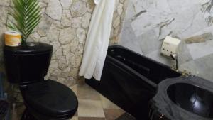 a bathroom with a black toilet and a sink at Boutique B&B at Stone Village in Bluefields