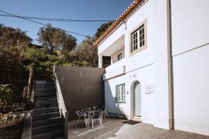 Casa blanca con escaleras, mesa y sillas en Encosta d´Óbidos, en Óbidos