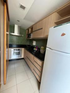 uma cozinha com um frigorífico branco e armários de madeira em Hospede-se B21 Convention Flat Particular em Brasília