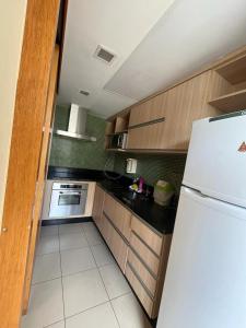eine Küche mit einem weißen Kühlschrank und Holzschränken in der Unterkunft Hospede-se B21 Convention Flat Particular in Brasilia