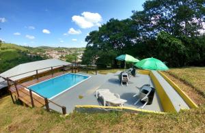 a swimming pool with two umbrellas and chairs at Pousada Solar da Montanha in Pedreira
