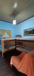 a room with a blue wall with a table and bunk beds at Pousada Matriz in São Thomé das Letras