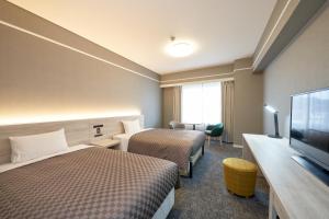 a hotel room with two beds and a flat screen tv at The OneFive Garden Kurashiki in Kurashiki