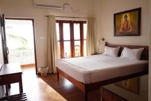 um quarto com uma cama grande e uma janela em Buddha Beach Hotel em Kovalam