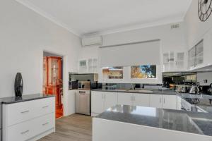 una gran cocina blanca con armarios y electrodomésticos blancos en Mabel’s retreat 4 bedrooms,Wifi,Netflix,Kayo, en Broken Hill