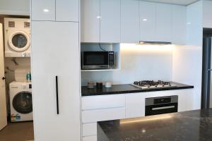 a white kitchen with a stove and a microwave at Kooii Apartments in Brisbane