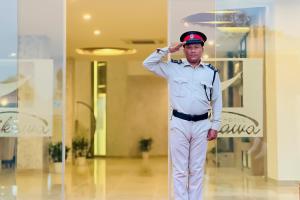 a man in a uniform standing in a room at Hotel Aikawa in Sauraha