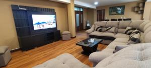 a living room with two couches and a flat screen tv at COMODO Y AMPLIO DEPARTAMENTO in Allpacoma