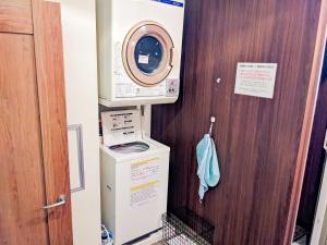 Hostel JIN - Weekly Appartment in Osaka في أوساكا: غسالة ومجفف في الغرفة
