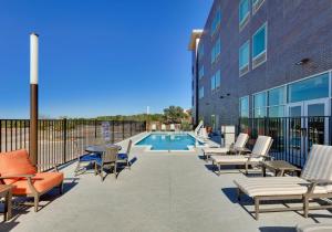 a patio with chairs and a pool in front of a building at La Quinta Inn & Suites by Wyndham Lakeway in Lakeway