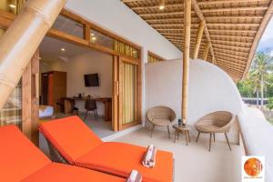 a living room with an orange couch and chairs at Pearl Sunset Resort in Gili Trawangan