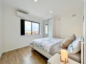 a white bedroom with a bed and a window at Brand new 2 Bedrooms Apartment in Ingleburn in Ingleburn
