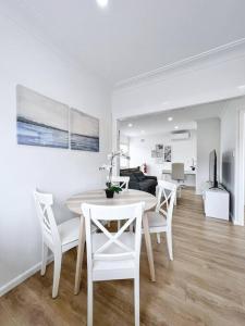 a white dining room with a table and chairs at Brand new 2 Bedrooms Apartment in Ingleburn in Ingleburn