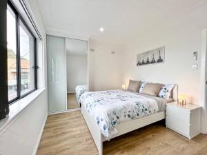 a white bedroom with a bed and a window at Brand new 2 Bedrooms Apartment in Ingleburn in Ingleburn
