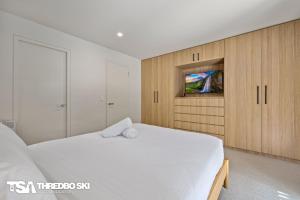 a bedroom with a white bed and a tv at Ironmongie 1 JackFrost in Thredbo