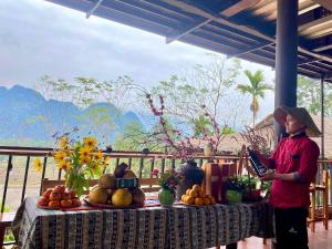 uma mulher de pé em frente a uma mesa com fruta em Inh La Home Pu Luong em Pu Luong