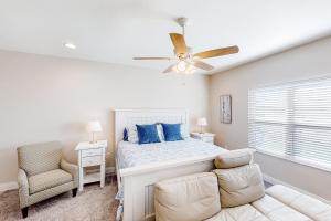 a white bedroom with a bed and a ceiling fan at Calm Waters - Carriage House in Santa Rosa Beach