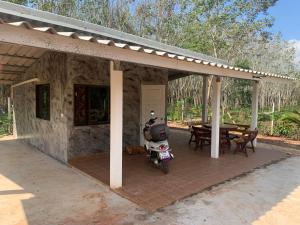 ein Haus mit einem Motorrad, das unter einer Terrasse geparkt ist in der Unterkunft NADOHN2 San Fan Homestay in Rayong