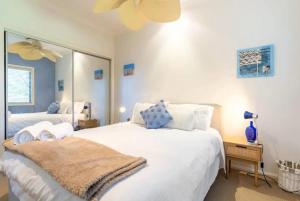 ein Schlafzimmer mit einem großen weißen Bett und einem Spiegel in der Unterkunft Eagles Nest Two Bed Home Nudgee Beach in Brighton