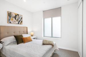 biała sypialnia z łóżkiem i oknem w obiekcie Moana Esplanade - Pure Beach Front 3 Bed Apt w mieście Moana