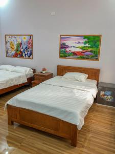 two beds in a room with paintings on the wall at Sohi Homestay in Quy Nhon