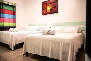 2 camas con ropa de cama blanca en una habitación en Hotel Playa Zipolite, en Zipolite