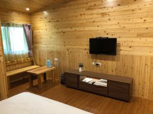 um quarto com uma parede de madeira, uma televisão e uma cama em Jingshan Landscape em Zhuolan