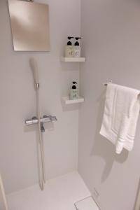 a white bathroom with a shower and white towels at ELE Hotel Ginza East in Tokyo