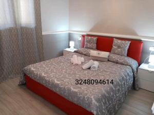 a bedroom with a large bed with a red headboard at Appartamento rosariomaria in Realmonte