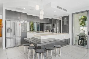 a kitchen with a counter and stools in it at Belle Escapes Tranquil Waters Luxury Home Palm Cove in Palm Cove