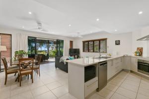 an open kitchen and living room with a table and chairs at Belle Escapes Ground Floor Beachfront Apartment in Yorkeys Knob