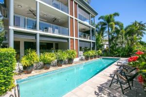 an apartment building with a swimming pool and plants at Belle Escapes Ground Floor Beachfront Apartment in Yorkeys Knob