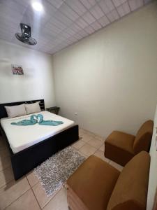 een slaapkamer met een bed, een stoel en een bank bij Los Sueños RyG 3 in Quepos