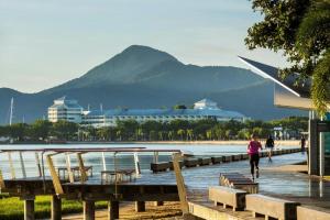 a woman walking on a dock next to the water at 604 Chic City Apartment with Water Views in Cairns