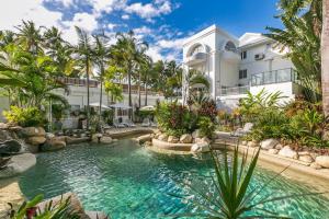 una piscina frente a una casa con palmeras en Belle Escapes Oceanview Suite 48 with Private Pool Alamanda Resort Palm Cove, en Palm Cove