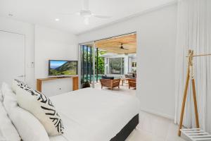 a bedroom with a white bed and a living room at Belle Escapes 94 Cascade Luxury Home Palm Cove in Palm Cove