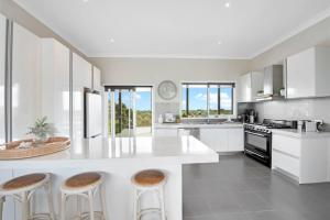 a kitchen with white cabinets and a large island with stools at Beachside House in Tootgarook