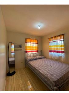 a bedroom with a bed and two windows at Hillview Apt w/ Pool Access - Free Wifi in Tagbilaran City