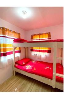 een slaapkamer met 2 stapelbedden met rode lakens bij Hillview Apt w/ Pool Access - Free Wifi in Tagbilaran-stad