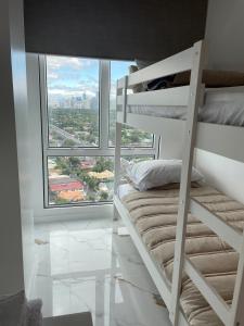 Etagenbett in einem Zimmer mit einem großen Fenster in der Unterkunft San Lorenzo Place in Manila