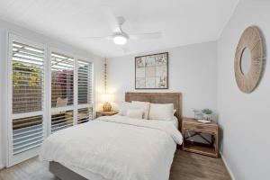 a white bedroom with a bed and a window at Peninsula Retreat in Rye