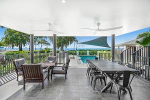 a patio with a table and chairs and a pool at Belle Escapes Beachfront Luxury Home 53 Arlington Clifton Beach in Palm Cove